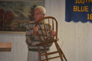 Jim Hoffman displays one of the original chairs that were purchased for the grange in 1896. They were purchased for a cost of $0.20 each.