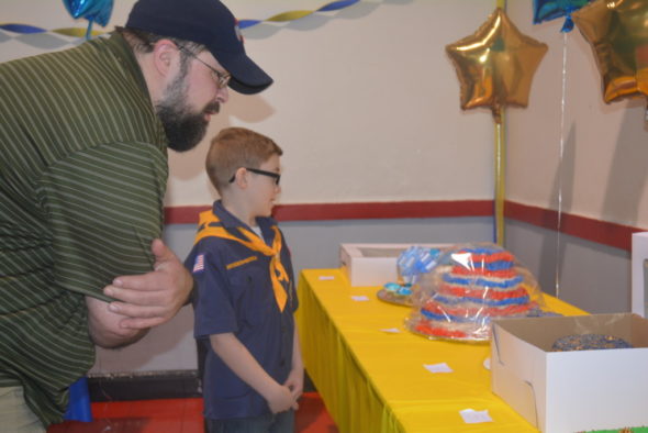 Ryder Milligan shows Kevin Cichon the cake he made for the Cub Scout birthday celebration at the annual Blue and Gold dinner. The cakes were later auctioned off to raise money for the Cub Scouts. 