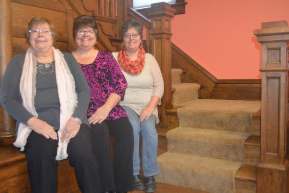 Sisters Jacque Wagner and Vickie Davis recently purchased the building at 204 S. Fourth St. to create a quilting retreat, which will open soon. They named the retreat after their mother. Pictured from left to right are: Sharon Henry, Davis, and Wagner sitting by the old staircase in the house with original woodwork.