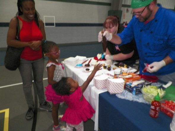 Marlie and Melanie Grant, daughters of Cie and Brandi Grant, carefully choose a cupcake and the frosting to decorate it with at the Responsible Fatherhood Event held at Kids America on June 17. 