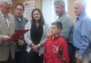 Mayor Steve Mercer, pictured at left, presented Colton Conkle (center) with a proclamation celebrating his Elks National Hoop Shoot title during the May 8 Coshocton City Council meeting. Standing behind them are members of city council. Josie Sellers | Beacon