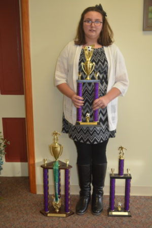 Bridgette Bible is the proud owner of back to back Elks National Soccer Shoot titles. She is pictured here holding her trophy from this year and at her feet are last year’s trophy plus the one she won that year for being the highest scorer. Josie Sellers | Beacon