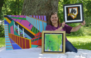 Katie Werner of Coshocton is pictured with a few pieces of her artwork. She is taking commissions for art pieces from the community starting this month. Artwork in the photo is not for sale.