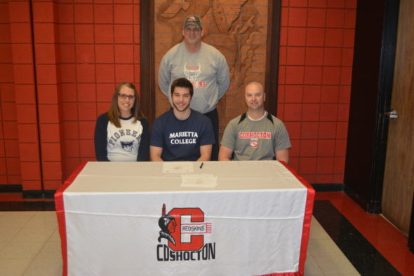 Coshocton High School senior Zach Michael, center, signed to play football at Marietta College. Pictured with him is his mom Monica and dad Fred. Behind them is CHS Head Football Coach Jim Woodrum. Josie Sellers | Beacon