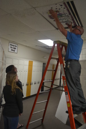 River View Junior High eighth graders Jennifer Roderick and Jessica Brooks watch as art teacher Rodney Stein installs the ceiling tile that Roderick decorated. Josie Sellers | Beacon