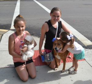 Rachel Levy, holding Gucci, and Hailey Tubbs with Suzie (who is getting a big hug from Lily Tubbs) are enjoying spending time together and showing off their dogs at the dog parade during the First Friday Celebration on July 7. Jen Jones | Beacon