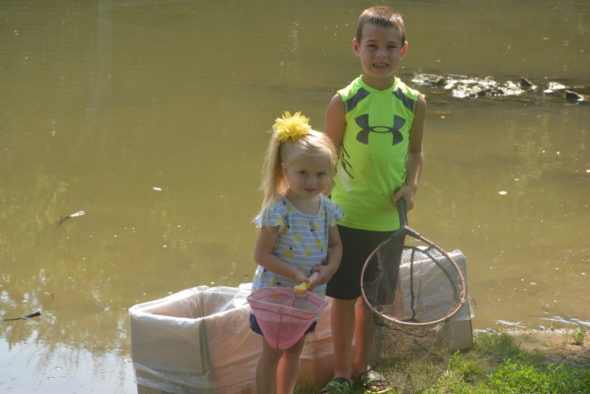 Jace Coffman, 6, and his sister Allie Coffman, 3, had the pleasure of helping the Coshocton City Recreation Department dump 1,000 fish into a pond by Kids America, where the public can now fish. Their Grandpa Coffman works for the city recreation department and invited them to come help with the project on July 18. Josie Sellers | Beacon