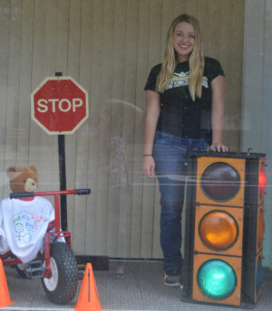 River View High School student Mackenzie Hudson used her senior class project to help promote the Red Cross, specifically its Safety City program and learn to swim lessons. She is pictured here after setting up a display for Safety City in the window of the United Way of Coshocton County office on Main Street. Josie Sellers | Beacon